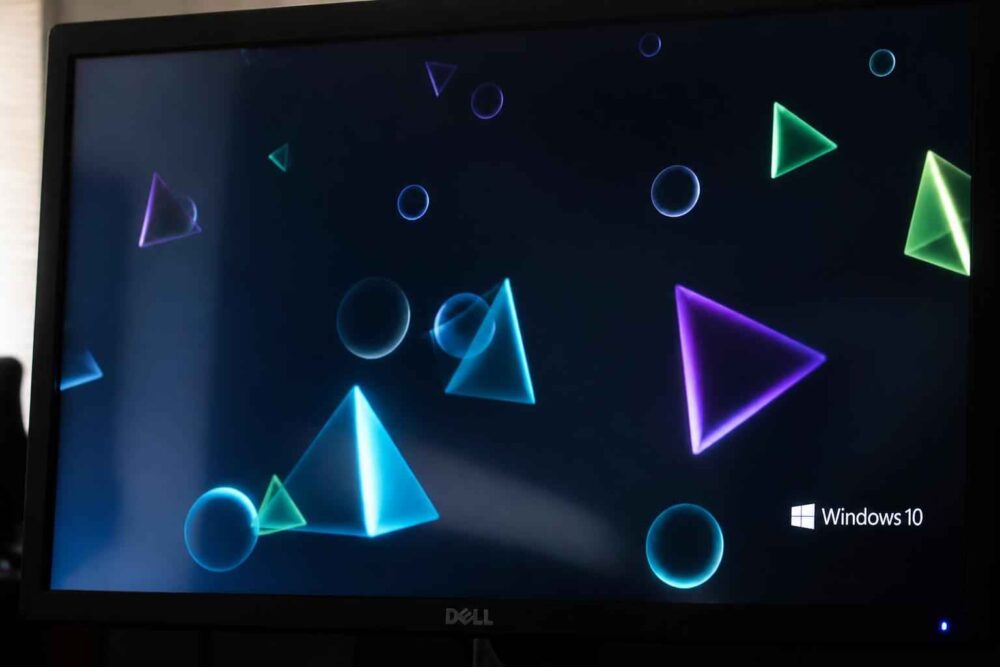Monitor Dell z podświetlonymi trójkątami i okręgami na ciemnym tle oraz logo Windows 10