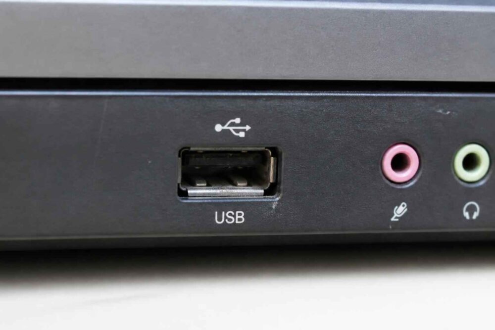 Przedni panel komputera z portem USB i gniazdami audio Czarny panel komputera z portem USB oraz różowym wejściem mikrofonowym i zielonym wyjściem słuchawkowym
