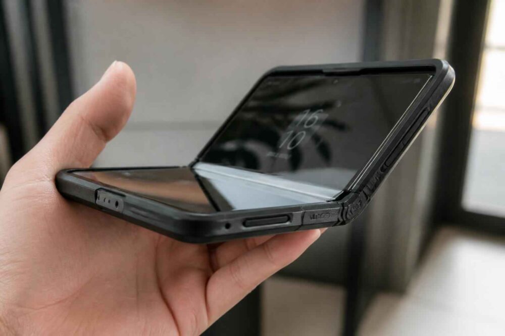 Rozłożony składany smartfon trzymany w dłoni, ukazany pod kątem z widocznym zawiasem i ekranem