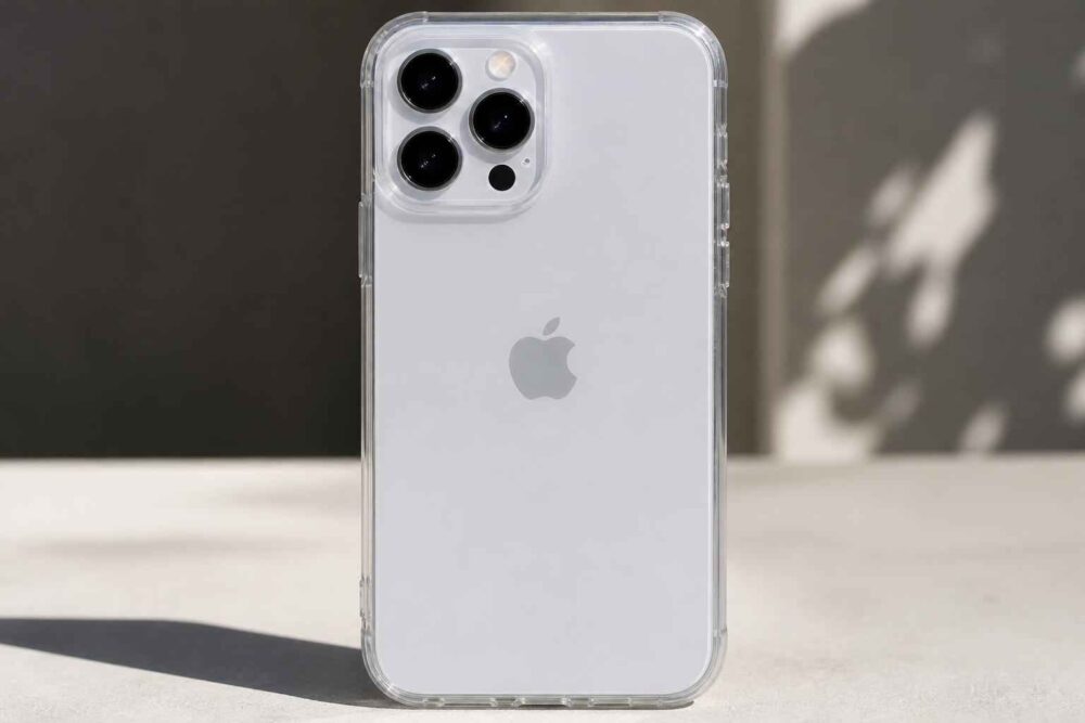 Srebrny iPhone z potrójnym aparatem w przezroczystym etui na jasnym blacie