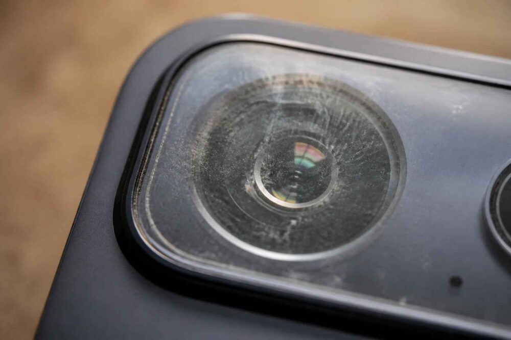 Zbliżenie na porysowany obiektyw aparatu w czarnym telefonie komórkowym