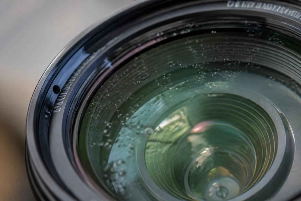 Zbliżenie szklanego obiektywu fotograficznego z widocznymi refleksami światła i pierścieniami soczewek